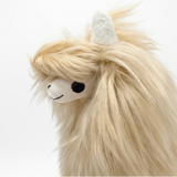 A close-up of a fluffy alpaca plush toy with cream-colored faux fur, a white face, and a black embroidered eye on a plain white background.