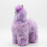 A fluffy lavender alpaca plush toy with small gray ears and a white beak, photographed against a clean white studio background.