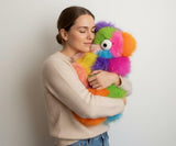 Woman holding a colorful fluffy toy against a plain background