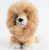 A fluffy alpaca fur lion plush toy with a light brown and cream-colored body, featuring a black nose, black whiskers, and a small white tail, photographed against a seamless white background.