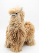 A fluffy alpaca plush toy with long tan and cream fur, standing against a seamless white background.