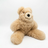 A fluffy teddy bear alpaca toy in a beige color, sitting against a seamless white studio background.