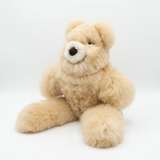 A plush teddy bear with fluffy light tan fur, sitting against a seamless white studio background.