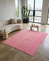 Living room with a pink rug, beige sofa, and potted plants.