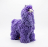 A plush purple alpaca stuffed animal with a soft, fluffy texture, seated against a blue background.