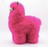 A bright hot pink fluffy alpaca plush toy with small gray ears, black eyes, and a white muzzle, standing against a plain white background.