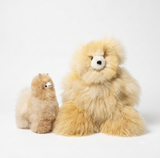 Two fluffy plush alpaca toys in light tan and cream tones, photographed on a clean white studio background.