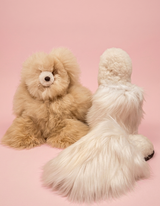 Beige alpaca stuffed bear and white Suri fur slippers luxury gift bundle on pink background.