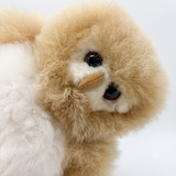 A close-up of a fluffy owl plush toy with cream-colored fur, large dark eyes, and a small stitched nose, photographed against a plain light background.