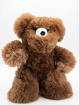 A brown curly-haired alpaca plush teddy bear with a single white eye and black nose, sitting against a plain white background.