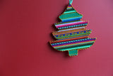 A multicolored Andean Inca tree-shaped ornament with a red background.