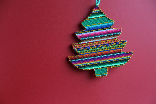 A multicolored Andean Inca tree-shaped ornament with a red background.