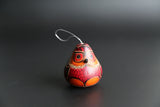 A hand-carved and hand-painted red owl ornament with a silver hook, against a black background.