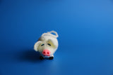 Hand Knitted Pig ornament with pink nose on a blue background.