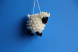 Hand knitted Ornament Sheep on white and black on a blue background