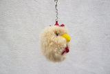 A beige alpaca fur keychain in the shape of a chicken with a red comb, yellow beak, black eyes, and red wattle, hanging against a neutral background.