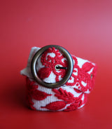 hand-woven white and red wool belt with vibrant floral embroidery.