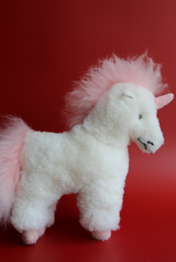 Handmade white alpaca stuffed toy with a pink mane and tail standing against a red background.